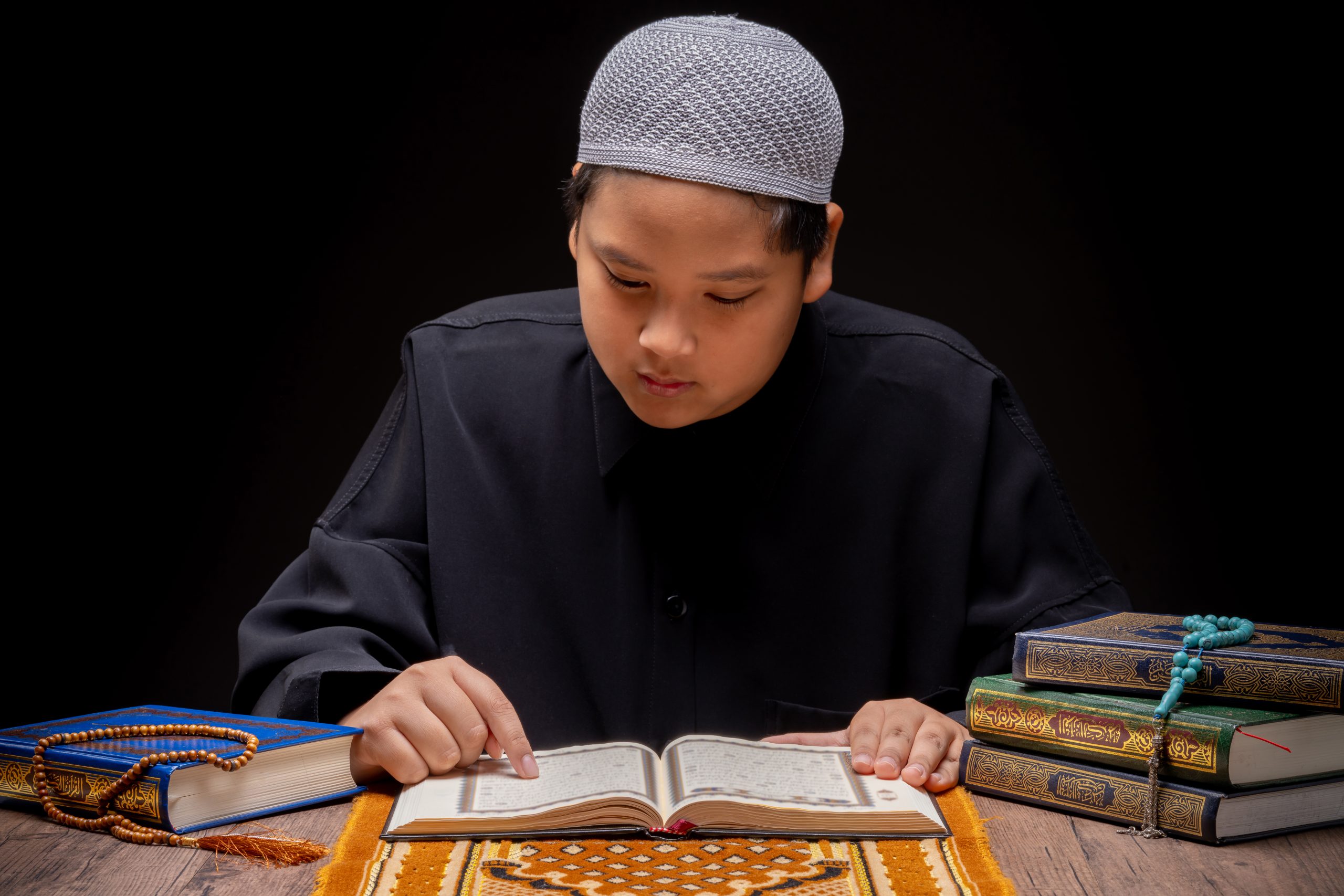 vecteezy_a-little-asian-muslim-boy-is-sitting-and-reading-the-quran_52112766